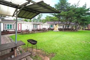 a park with picnic tables and a chair under an umbrella at Sungbochon Youth Hostel - Hostel in Mungyeong