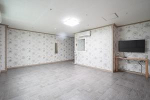 an empty room with a tv on the wall at Sungbochon Youth Hostel - Hostel in Mungyeong