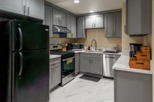 a kitchen with white cabinets and a black refrigerator at Spacious Disneyland Getaway I Game Room, King Suites & EV Access I Sleeps 14 in Midway City