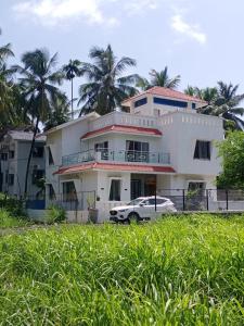 Una casa blanca con un coche aparcado delante. en Adviks Home Stay, en Alibaug 4 fotos más