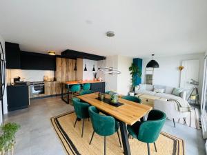 a kitchen and living room with a wooden table and green chairs at Luxe,calme et volupté in Publier