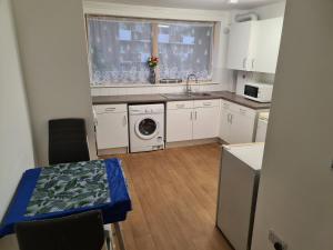 a kitchen with white cabinets and a table and a sink at Lascelles house - a few mins to US Embassy, Battersea Power Station & Central London in London
