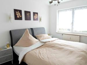 ein Schlafzimmer mit einem Bett mit weißer Bettwäsche und einem Fenster in der Unterkunft Bodenseeperle in Friedrichshafen