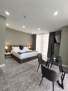 マプトにあるPolana Plaza Hotelのベッド、デスク、椅子が備わるホテルルームです。