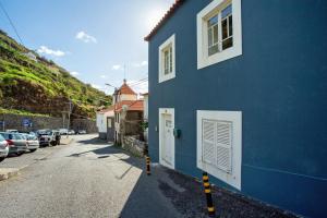 a blue building on a street with cars parked at Calheta Beach House T2 in Calheta
