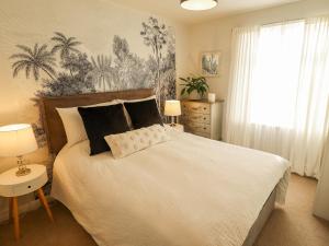a bedroom with a bed and a window with palm trees at Lavender Cottage in Louth