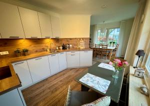 a kitchen with white cabinets and a table with flowers on it at De Bonte Specht in Nijverdal
