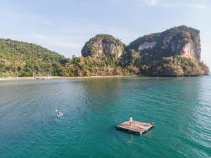 zwei Menschen auf einer Anlegestelle im Wasser mit Bergen in der Unterkunft Paradise Koh Yao in Ko Yao Noi