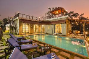 a house with a swimming pool and some chairs at SaffronStays Dew Drops - 5BR pet-friendly villa with pool, gym, gazebo & Kikvi River views in Karjat in Dhamni