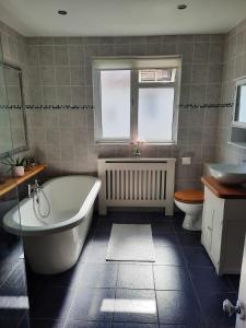 a bathroom with a tub and a toilet and a sink at Super king bedroom with large ensuite in Brighton & Hove