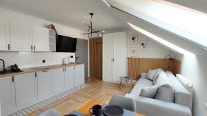 a living room with a white couch and a kitchen at Cicha 3 in Sztutowo