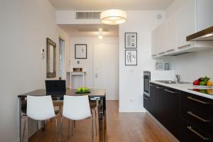 a kitchen with a dining table and white chairs at MoBiRetreat by Klodge in Olbia