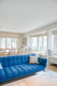 a blue couch in a living room with chairs at Stunning 3-Bedroom apartment with panoramic view in De Haan