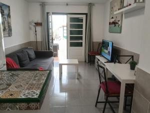 a living room with a couch and a desk with a computer at Puerta del sol in Caleta De Fuste
