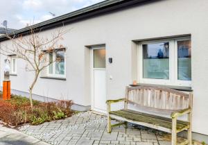 a wooden bench in front of a white house at Gästewohnung Köln-Longerich in Cologne