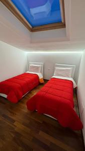 two beds in a room with red sheets at 085 luxury apartment in Montesilvano