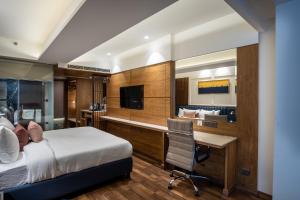 a bedroom with a bed and a desk and a television at The Kleo Hotel in Zirakpur