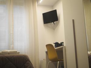 a bedroom with a chair and a television on the wall at A casa di Giotto in Bologna