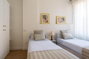 two beds in a room with white walls at Sweet Home Santander in Santander
