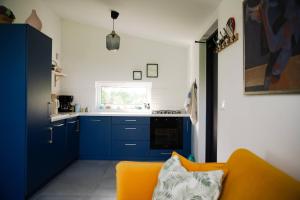a kitchen with blue cabinets and a yellow couch at Pilwa 17 - Domek in Pilwa