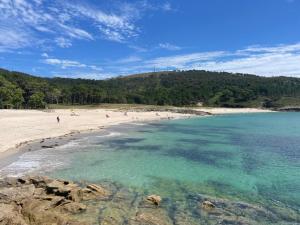 a beach with a group of people in the water at Grupo Gontad Apartamento Mourelle Corme in Corme-Puerto