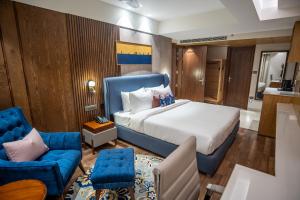 a bedroom with a large bed and a blue chair at The Kleo Hotel in Zirakpur +24 photos