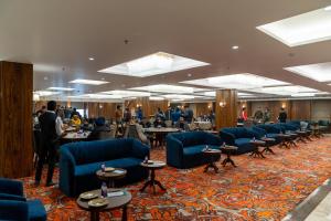 a large room with blue chairs and tables and people at The Kleo Hotel in Zirakpur