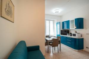 a living room with a blue couch and a kitchen at Gioberti Flat - WiFi - City Center - Shopping Street - Casino - Ariston in Sanremo