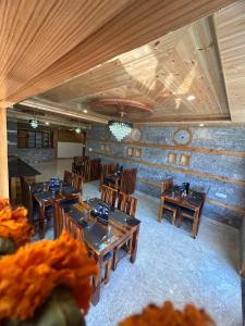 Un restaurante con mesas y sillas de madera en una sala. en LN Grand Suite, en Manali