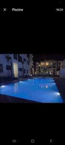 a picture of a large blue swimming pool at night at Appartement Moderne et Confortable in Bouznika