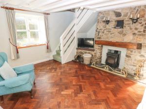 ein Wohnzimmer mit einem Steinkamin und einem blauen Stuhl in der Unterkunft Barn Cottage in Spittal