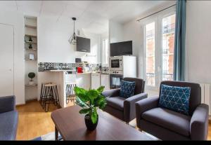 a living room with couches and a table and a kitchen at Le Raspail - Charmant appartement proche Paris in Levallois-Perret