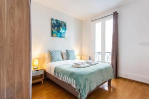 a bedroom with a bed and a large window at Le Raspail - Charmant appartement proche Paris in Levallois-Perret