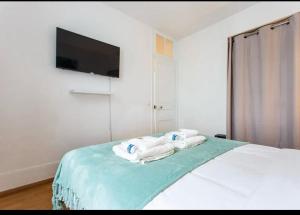 a bedroom with towels on a bed with a flat screen tv at Le Raspail - Charmant appartement proche Paris in Levallois-Perret