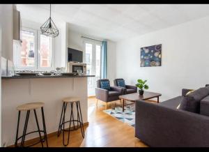 a kitchen and a living room with a couch and a table at Le Raspail - Charmant appartement proche Paris in Levallois-Perret