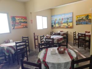 a dining room with tables and chairs and paintings on the walls at Hotel Veleiro de Porto in Porto De Galinhas