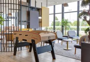 una mesa de ping pong en una habitación con sillas en B&B HOTEL Reims Croix Blandin, en Reims