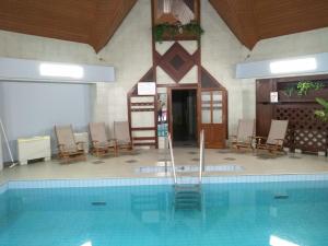 a swimming pool in a building with chairs and a table at Odvaskő Panzió in Ugod