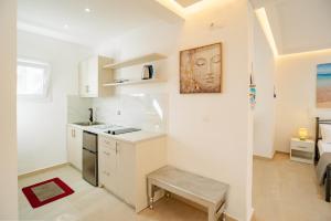a kitchen with white cabinets and a bench in a room at Angelina Studios in Lefkímmi