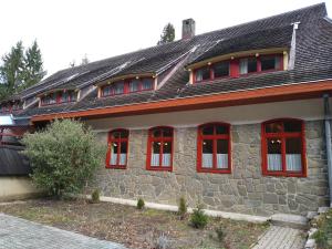 a stone house with red windows and a gray roof at Odvaskő Panzió in Ugod