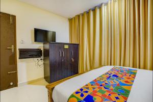 a bedroom with a bed and a tv and curtains at Via Rithun Residency - Jayanagar Anjaneyaswamy Temple in Bangalore