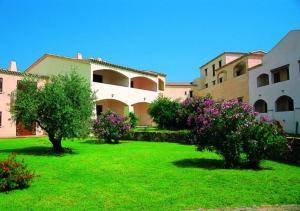 a green yard with trees and flowers in front of a building at Marinella Residence in Santa Marinella