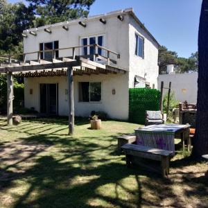 una casa blanca con un banco en el patio en Siempre bien, en Balneario Buenos Aires