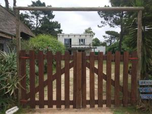 una valla de madera con una casa en el fondo en Siempre bien, en Balneario Buenos Aires