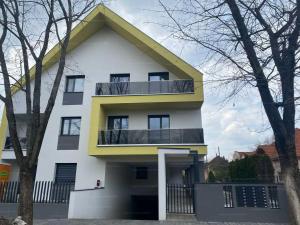 a white and yellow house with a balcony at Gold Residence Apartman in Hajdúszoboszló