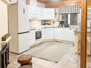 a kitchen with white cabinets and a white refrigerator at Holiday Home Tahkontupa by Interhome in Tahkovuori