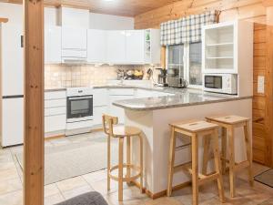 a kitchen with white cabinets and bar stools at Holiday Home Tahkontupa by Interhome in Tahkovuori