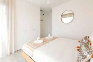 ein weißes Schlafzimmer mit einem großen Bett und einem Spiegel in der Unterkunft Consolação Sunset View in Atouguia da Baleia
