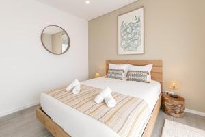 Schlafzimmer mit einem großen weißen Bett und einem Spiegel in der Unterkunft Consolação Sunset View in Atouguia da Baleia