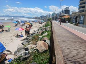 einen Strand mit Menschen auf dem Sand und eine Promenade in der Unterkunft Gostosa casa de praia, à 700 metros da Meia-Praia in Navegantes